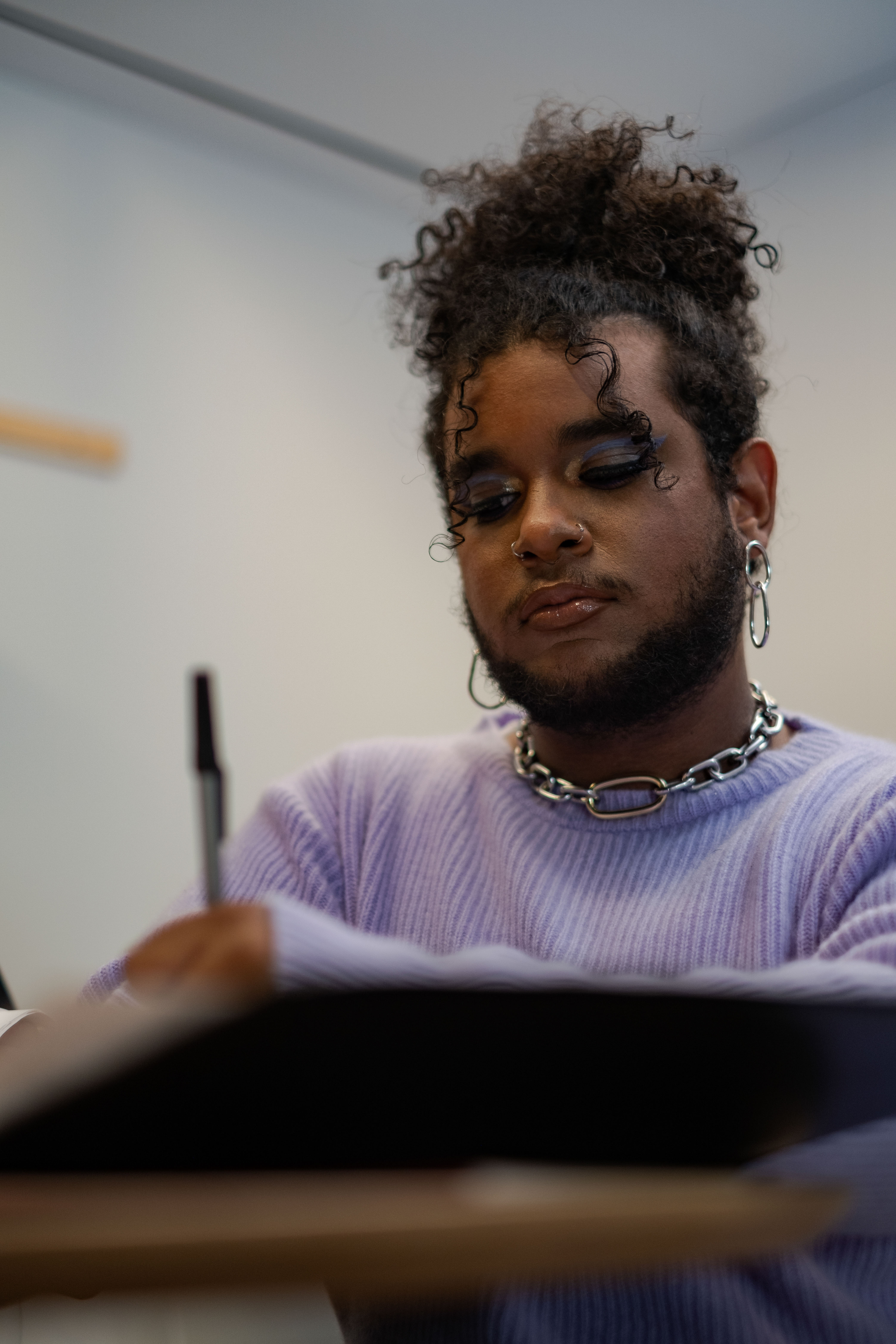 A non-binary person writing in a notepad